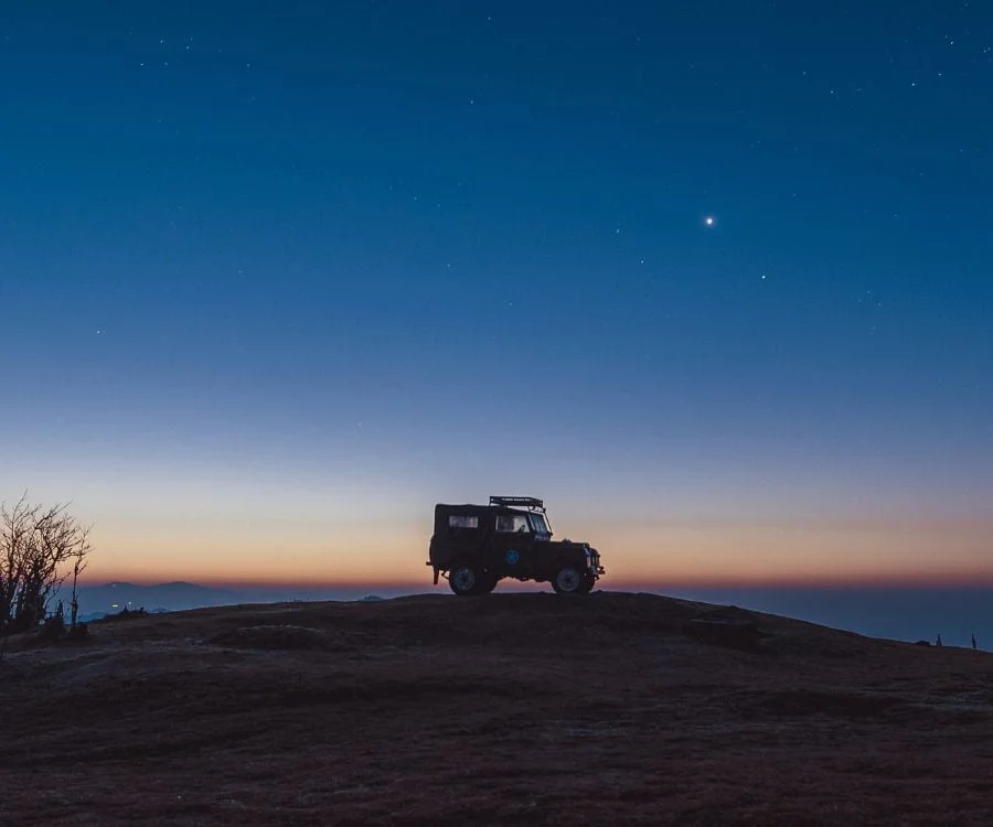 Silhouettes of a jeep with a sunset sky as a backdrop.